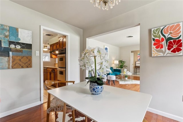 6301 Schouest St, Metairie, LA 70003 - dining area featuring wood finished floors, baseboards, and a chandelier