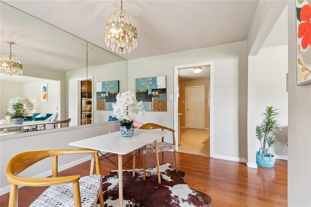 6301 Schouest St, Metairie, LA 70003 - dining room featuring a chandelier, baseboards, and wood finished floors