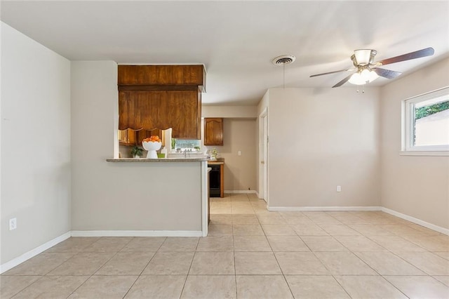 6301 Schouest St, Metairie, LA 70003 - kitchen with a ceiling fan, brown cabinetry, light tile patterned floors, baseboards, and light countertops