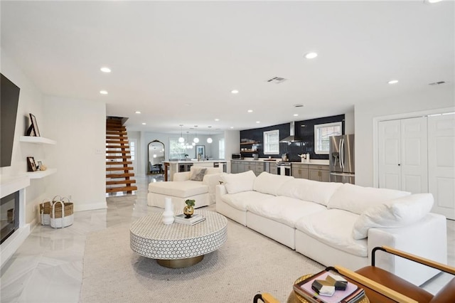 5537 Cherlyn Dr, New Orleans, LA 70124 - living room featuring recessed lighting, healthy amount of natural light, a glass covered fireplace, a chandelier, and light marble finish floors