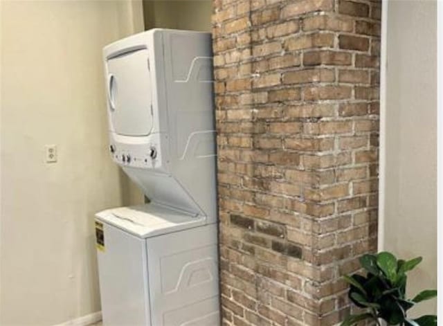 1740 Abundance St, New Orleans, LA 70119 - laundry area with stacked washer and clothes dryer, baseboards, and brick wall