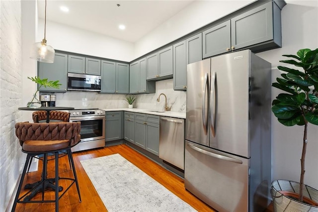 633 Tchoupitoulas St Unit 4, New Orleans, LA 70130 - kitchen featuring appliances with stainless steel finishes, a sink, wood finished floors, backsplash, and light countertops
