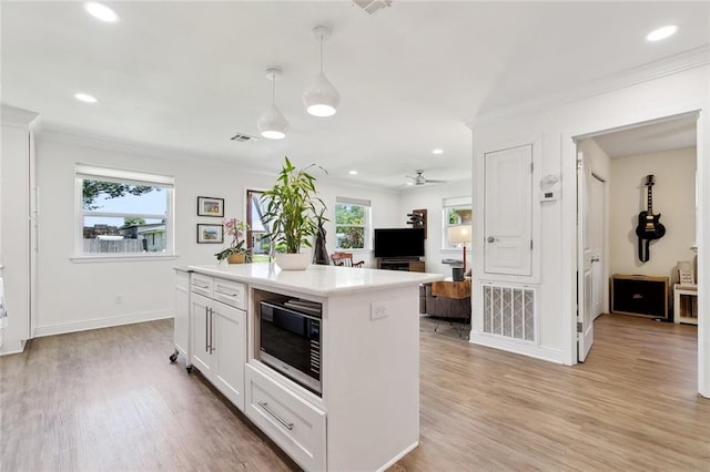 917 Belmont Pl, Metairie, LA 70001 - kitchen with stainless steel microwave, crown molding, light wood-type flooring, light countertops, and decorative light fixtures