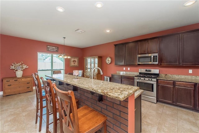 422 Scotch Pine Dr, Ponchatoula, LA 70454 - kitchen featuring stainless steel appliances, light tile patterned flooring, light stone countertops, a breakfast bar area, and dark brown cabinetry