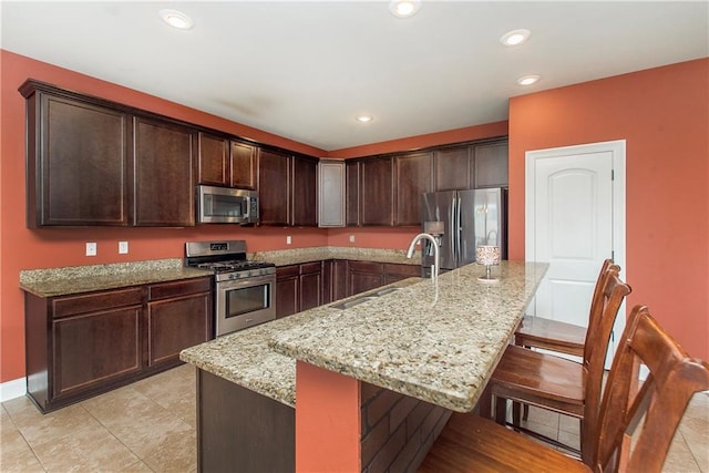 422 Scotch Pine Dr, Ponchatoula, LA 70454 - kitchen with stainless steel appliances, a sink, a kitchen bar, light stone counters, and dark brown cabinets
