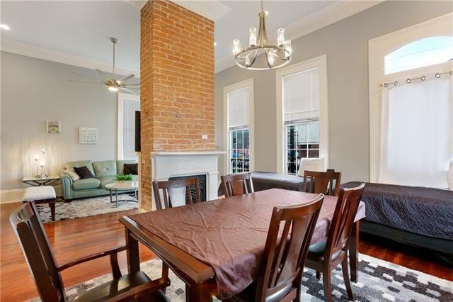 1355 Columbus St, New Orleans, LA 70116 - dining room with wood finished floors, a chandelier, a fireplace, ceiling fan, and crown molding