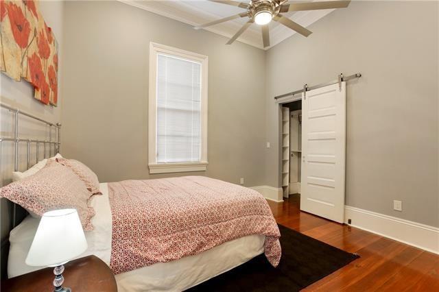 1355 Columbus St, New Orleans, LA 70116 - bedroom with a barn door, wood finished floors, and a ceiling fan