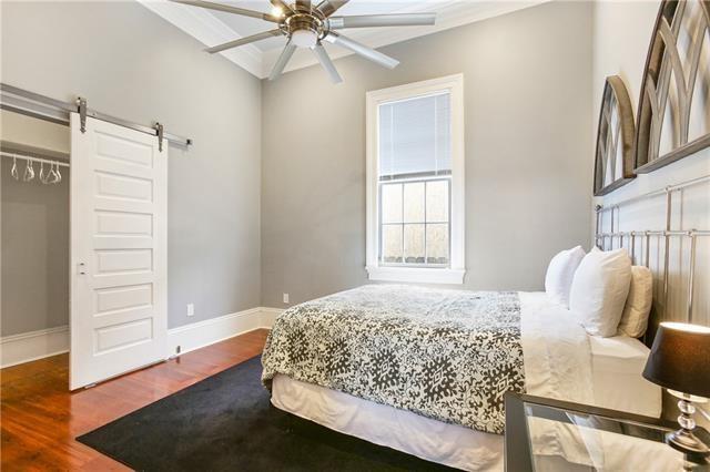 1355 Columbus St, New Orleans, LA 70116 - bedroom with wood finished floors, a barn door, crown molding, and a ceiling fan