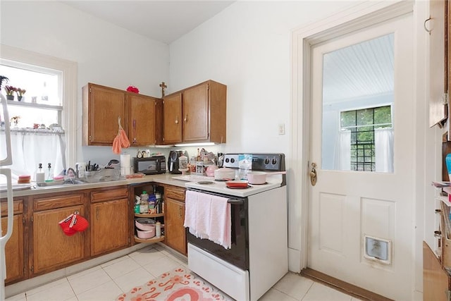 5655 Hawthorne Pl, New Orleans, LA 70124 - kitchen with white range with electric stovetop, brown cabinetry, black microwave, light tile patterned flooring, and light countertops