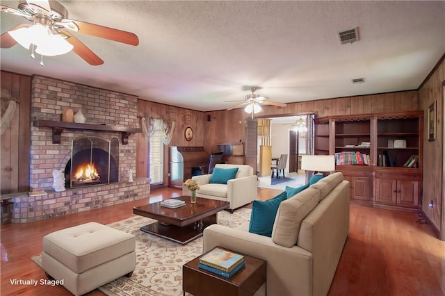 477 S Church St, Garyville, LA 70051 - living area featuring a ceiling fan, a fireplace, wooden walls, a textured ceiling, and light wood-style flooring