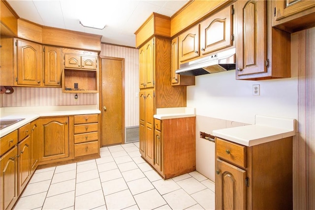 477 S Church St, Garyville, LA 70051 - kitchen featuring under cabinet range hood, brown cabinetry, light tile patterned flooring, light countertops, and wallpapered walls
