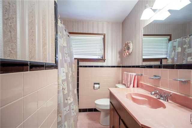 477 S Church St, Garyville, LA 70051 - bathroom with wallpapered walls, toilet, vanity, tile walls, and wainscoting