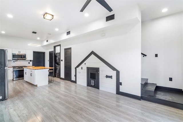 5400 N Rampart St, New Orleans, LA 70117 - kitchen featuring appliances with stainless steel finishes, butcher block countertops, stacked washer / dryer, white cabinetry, and a ceiling fan