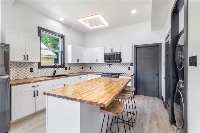 5400 N Rampart St, New Orleans, LA 70117 - kitchen featuring appliances with stainless steel finishes, wood counters, a sink, stacked washer / dryer, and a kitchen breakfast bar