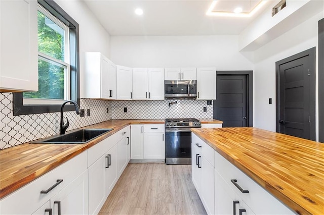 5400 N Rampart St, New Orleans, LA 70117 - kitchen featuring wood counters, appliances with stainless steel finishes, a sink, backsplash, and white cabinets