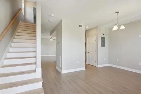 4021 N Rocheblave St, New Orleans, LA 70117 - staircase featuring wood finished floors, electric panel, baseboards, a chandelier, and ceiling fan
