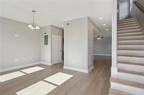 4021 N Rocheblave St, New Orleans, LA 70117 - unfurnished dining area featuring stairs, wood finished floors, a chandelier, baseboards, and ceiling fan
