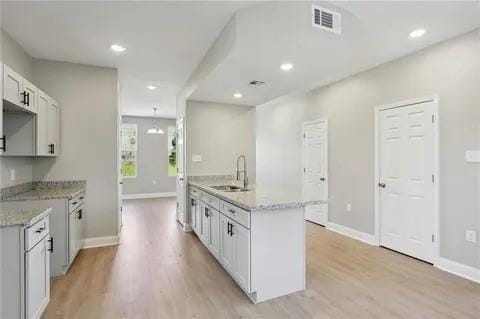 4021 N Rocheblave St, New Orleans, LA 70117 - kitchen featuring a sink, light wood-style flooring, recessed lighting, baseboards, and white cabinetry