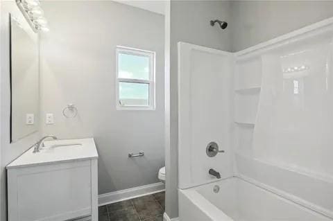 4021 N Rocheblave St, New Orleans, LA 70117 - bathroom with vanity, washtub / shower combination, toilet, baseboards, and tile patterned floors
