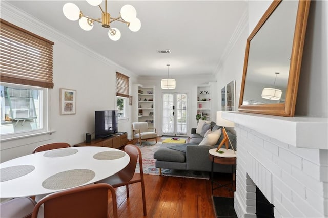 304 Henry Clay Ave, New Orleans, LA 70118 - dining space featuring a fireplace, ornamental molding, dark wood-style floors, built in shelves, and a chandelier