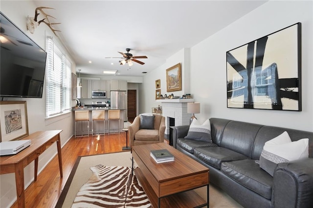 304 Henry Clay Ave, New Orleans, LA 70118 - living room with light wood-style floors, a ceiling fan, and a brick fireplace