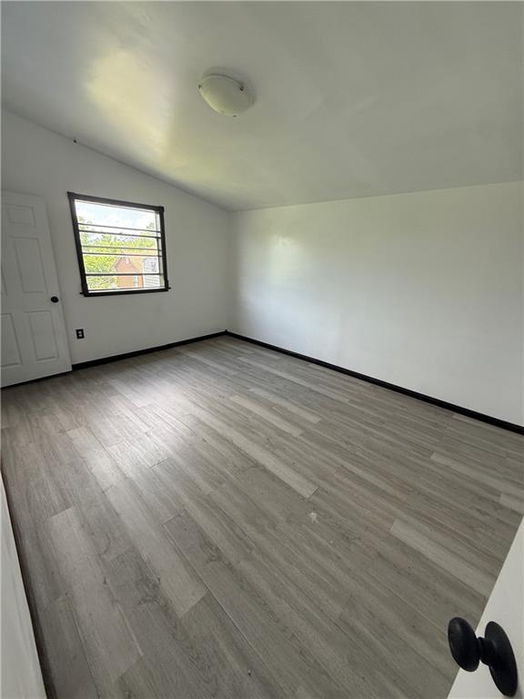 5022 Mcmurtry St, Marrero, LA 70072 - unfurnished room featuring lofted ceiling, wood finished floors, and baseboards