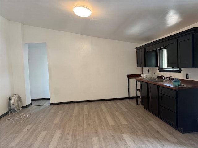 5022 Mcmurtry St, Marrero, LA 70072 - kitchen with dark cabinets, light wood-style flooring, a sink, dark countertops, and baseboards