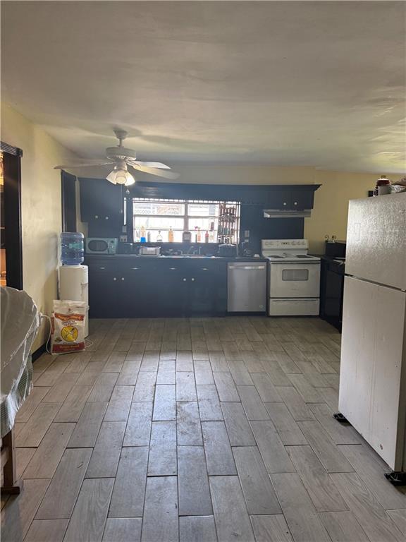 5022 Mcmurtry St, Marrero, LA 70072 - kitchen with white appliances, a ceiling fan, and wood finished floors