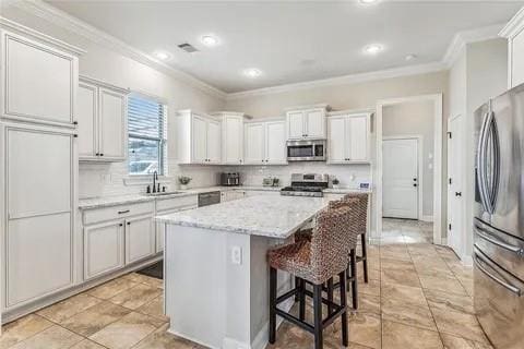 298 Saw Grass Loop, Covington, LA 70435 - kitchen featuring appliances with stainless steel finishes, ornamental molding, a sink, a center island, and a breakfast bar area