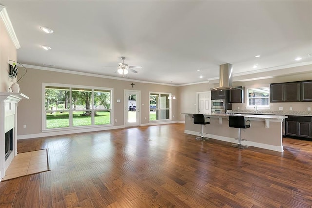 15488 Lake Ramsey Rd, Covington, LA 70435 - unfurnished living room with dark wood-style floors, ceiling fan, ornamental molding, a fireplace with flush hearth, and baseboards