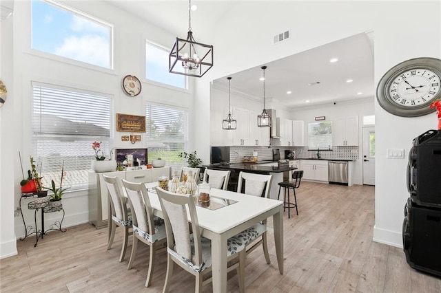 67 W Claiborne Sq, Chalmette, LA 70043 - dining area featuring a chandelier, light wood-style flooring, healthy amount of natural light, a towering ceiling, and recessed lighting