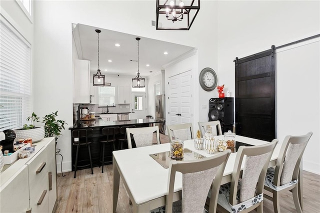 67 W Claiborne Sq, Chalmette, LA 70043 - dining room featuring light wood-style flooring, a high ceiling, a chandelier, recessed lighting, and baseboards