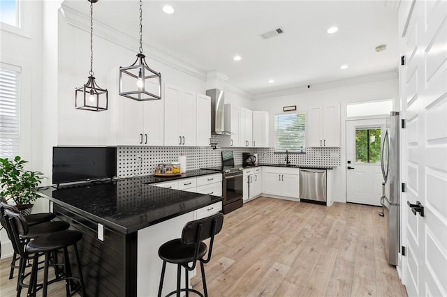 67 W Claiborne Sq, Chalmette, LA 70043 - kitchen featuring appliances with stainless steel finishes, wall chimney exhaust hood, a breakfast bar area, dark countertops, and recessed lighting