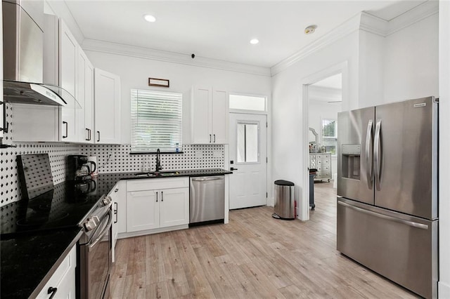 67 W Claiborne Sq, Chalmette, LA 70043 - kitchen featuring stainless steel appliances, wall chimney exhaust hood, a sink, decorative backsplash, and white cabinetry