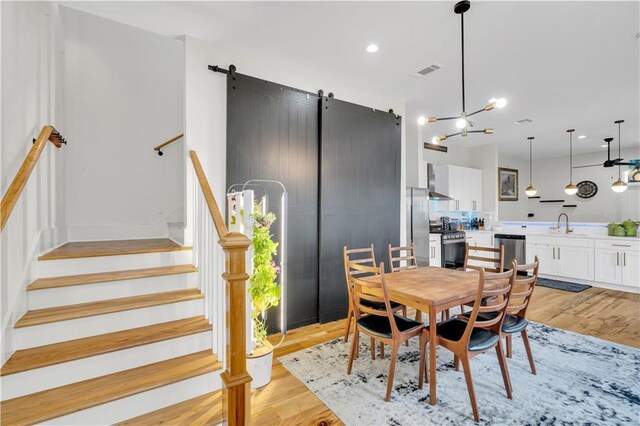 1039 Verret St, New Orleans, LA 70114 - dining space featuring a barn door, light wood-style flooring, stairway, and recessed lighting