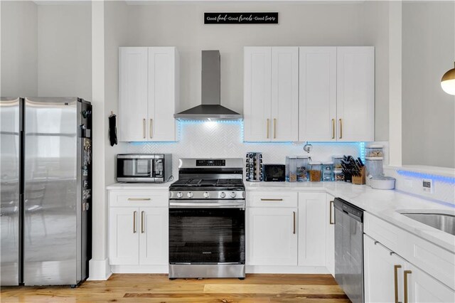 1039 Verret St, New Orleans, LA 70114 - kitchen featuring appliances with stainless steel finishes, wall chimney range hood, white cabinetry, and backsplash