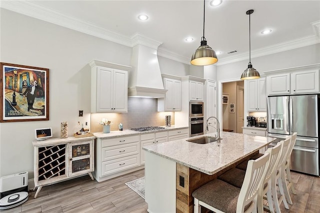 596 Blue Heron Ln, Madisonville, LA 70447 - kitchen with stainless steel appliances, a sink, white cabinets, light stone counters, and light wood-type flooring