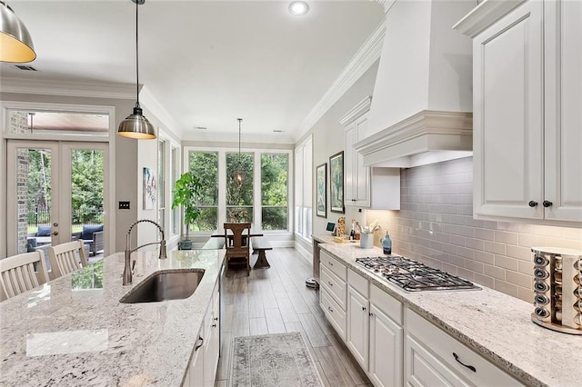 596 Blue Heron Ln, Madisonville, LA 70447 - kitchen with a sink, premium range hood, stainless steel gas cooktop, tasteful backsplash, and white cabinetry
