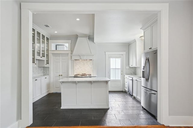 4198 Dumaine St, New Orleans, LA 70119 - kitchen with stainless steel fridge, decorative backsplash, glass insert cabinets, a kitchen island, and ornamental molding