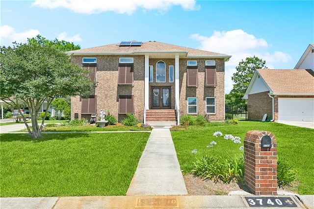 3740 Lake Lynn Dr, Gretna, LA 70056 - view of front of home with solar panels, a front lawn, french doors, a garage, and brick siding
