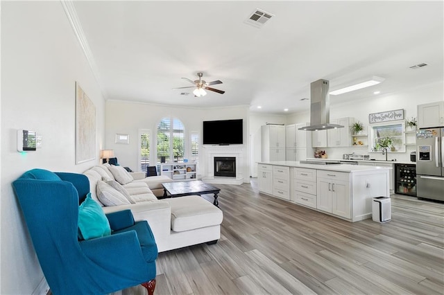 3740 Lake Lynn Dr, Gretna, LA 70056 - living area featuring ornamental molding, a fireplace with raised hearth, ceiling fan, light wood finished floors, and recessed lighting
