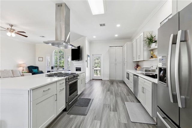 3740 Lake Lynn Dr, Gretna, LA 70056 - kitchen featuring stainless steel appliances, island range hood, open floor plan, ceiling fan, and ornamental molding