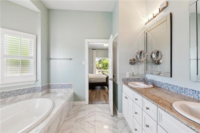 3740 Lake Lynn Dr, Gretna, LA 70056 - full bathroom featuring connected bathroom, double vanity, a bath, marble finish floors, and baseboards
