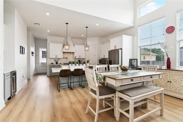 2535 Athis St, New Orleans, LA 70122 - dining room with wine cooler, light wood-type flooring, healthy amount of natural light, recessed lighting, and a high ceiling
