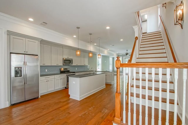 433 S Cortez St, New Orleans, LA 70119 - kitchen featuring appliances with stainless steel finishes, a sink, dark countertops, crown molding, and light wood-style floors