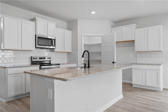 5357 Bypass Breeze Ave, Slidell, LA 70461 - kitchen featuring stainless steel appliances, a sink, light stone counters, light wood-style flooring, and decorative backsplash