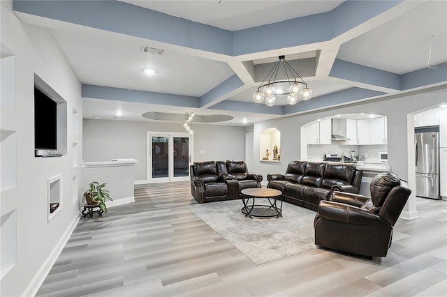 1713 Thomas St, Gretna, LA 70053 - living area featuring light wood-style flooring, coffered ceiling, a chandelier, and arched walkways
