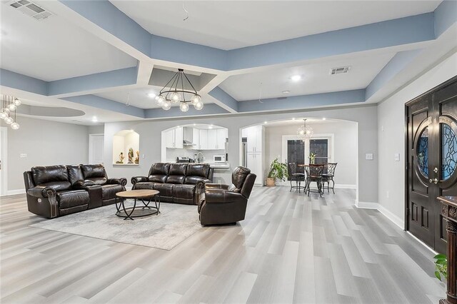1713 Thomas St, Gretna, LA 70053 - living room featuring arched walkways, a chandelier, light wood finished floors, and coffered ceiling