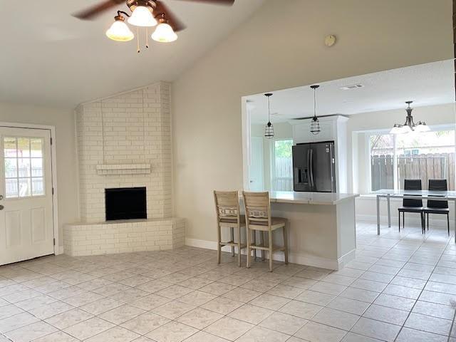 2120 Killington Dr, Harvey, LA 70058 - kitchen featuring fridge with ice dispenser, a ceiling fan, light tile patterned floors, a brick fireplace, and a peninsula