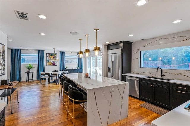 231 Audubon Blvd, New Orleans, LA 70125 - kitchen featuring stainless steel appliances, a sink, dark cabinetry, a kitchen island, and a kitchen breakfast bar